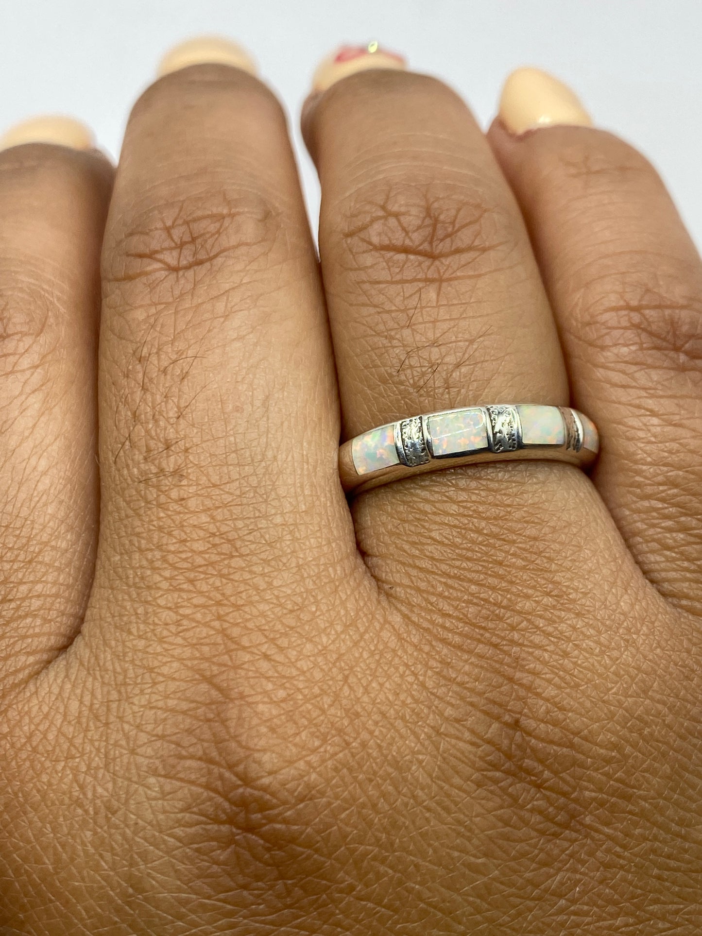 Anillo en dedo mostrando los destellos de fuego del ópalo bajo luz natural