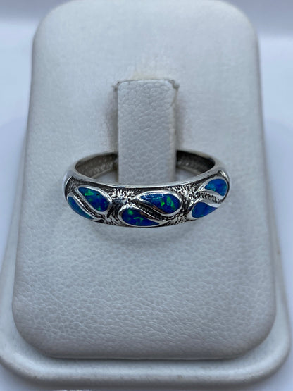 Anillo de plata .950 con ópalo de fuego azul engastado, sobre dedo de mujer
