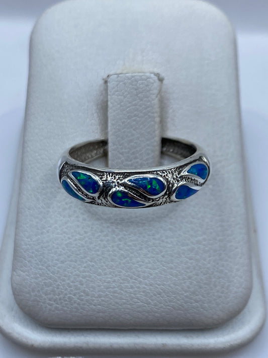 Anillo de plata .950 con ópalo de fuego azul engastado, sobre dedo de mujer