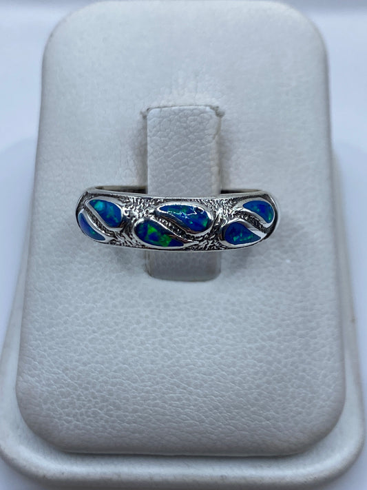 Anillo de plata .950 con ópalo de fuego azul engastado a mano, sobre estuche blanco