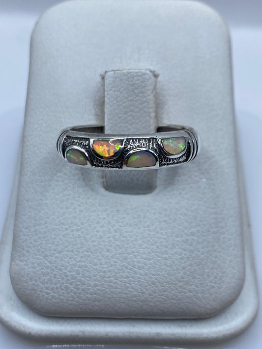Anillo de plata con Opalo de Fuego multicolor engastado a mano, vista frontal en joyero blanco