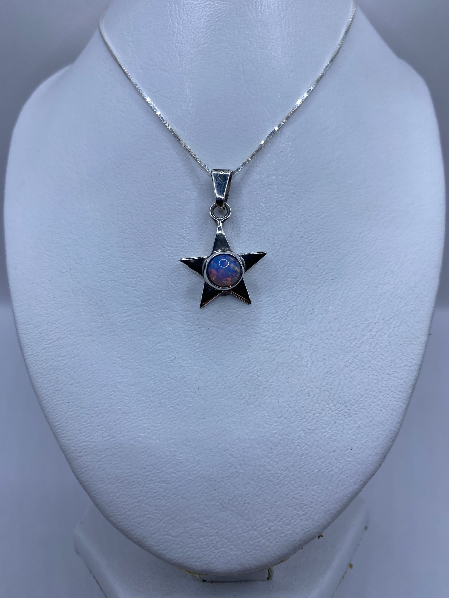 Detalle frontal del dije estrella mostrando el engaste de la piedra multicolor