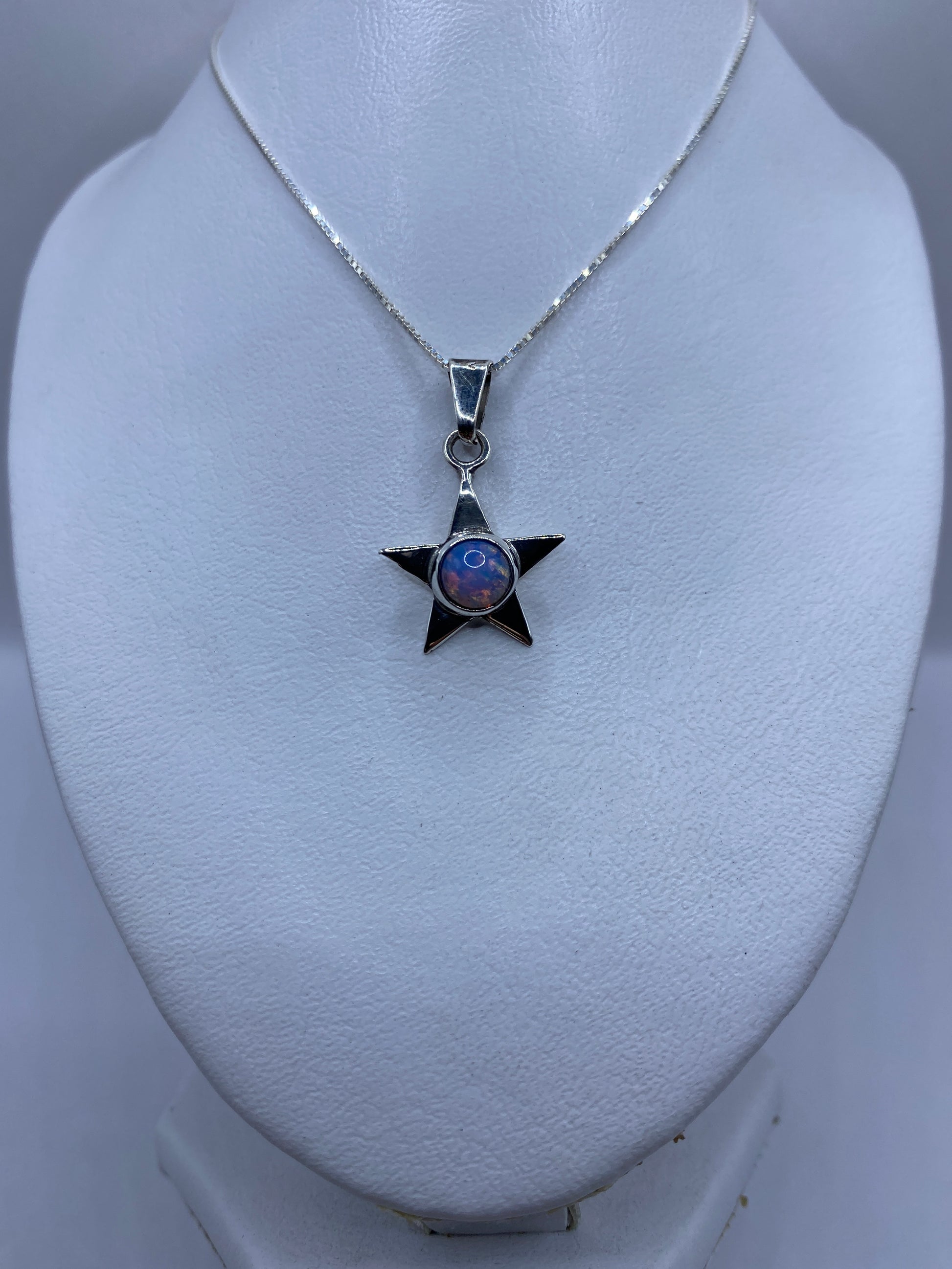 Detalle frontal del dije estrella mostrando el engaste de la piedra multicolor