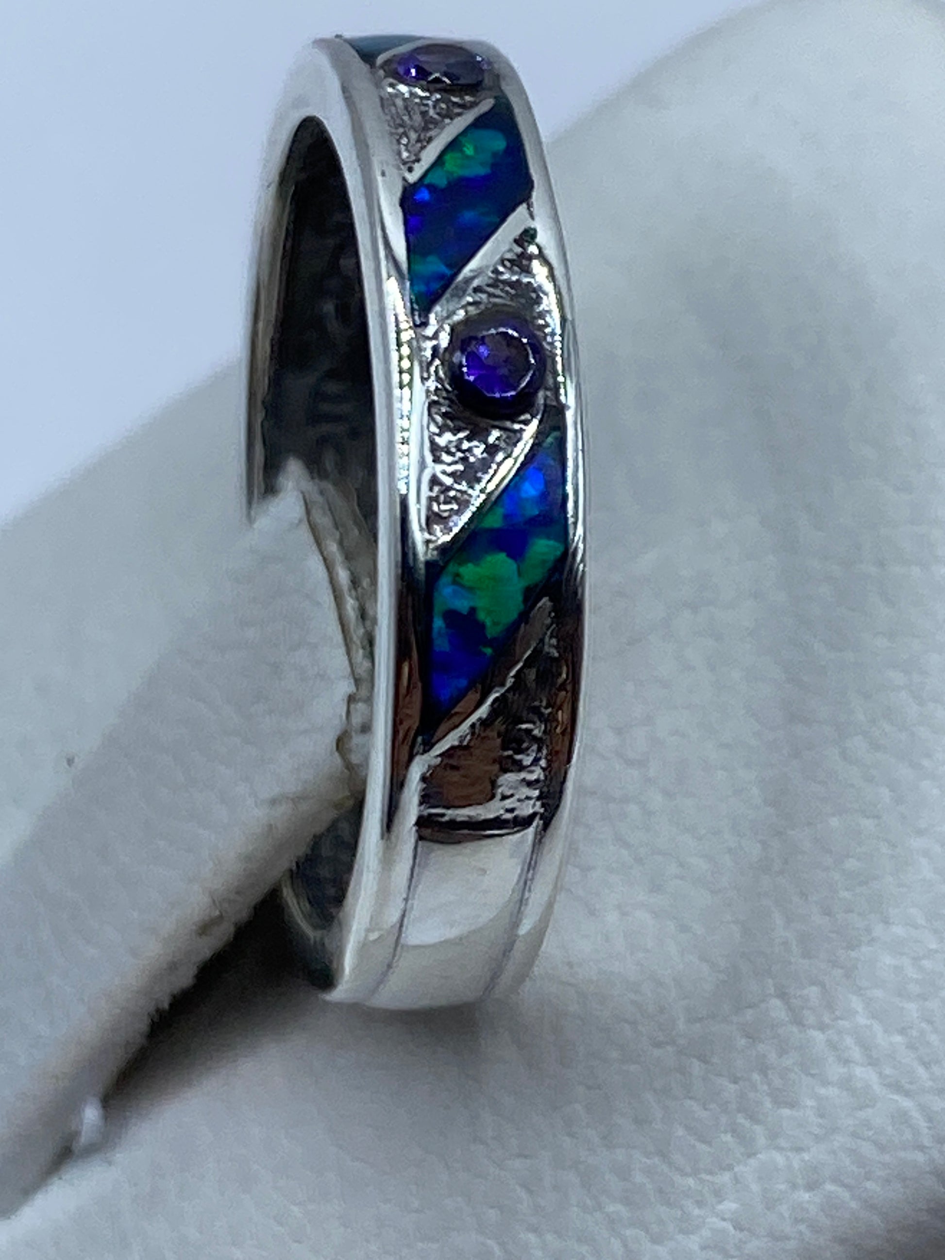 Anillo personalizado de plata .950 en dedo, mostrando los destellos azules del ópalo
