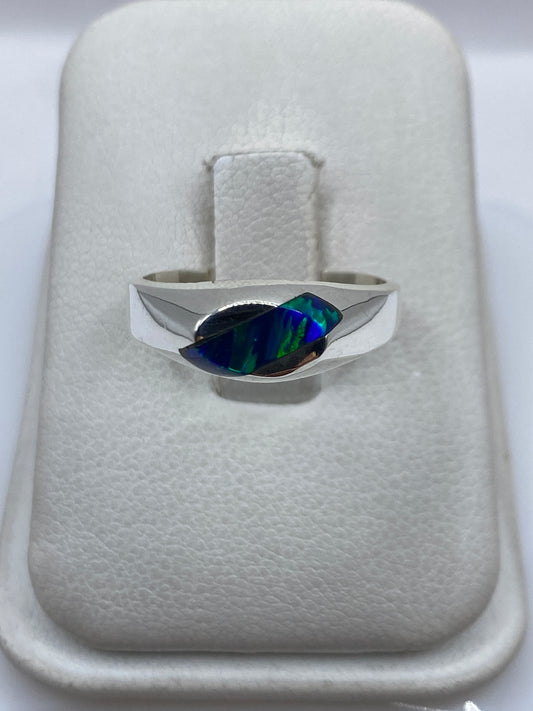 Anillo de plata .950 con ópalo de fuego azul intenso en mano, mostrando el juego de colores