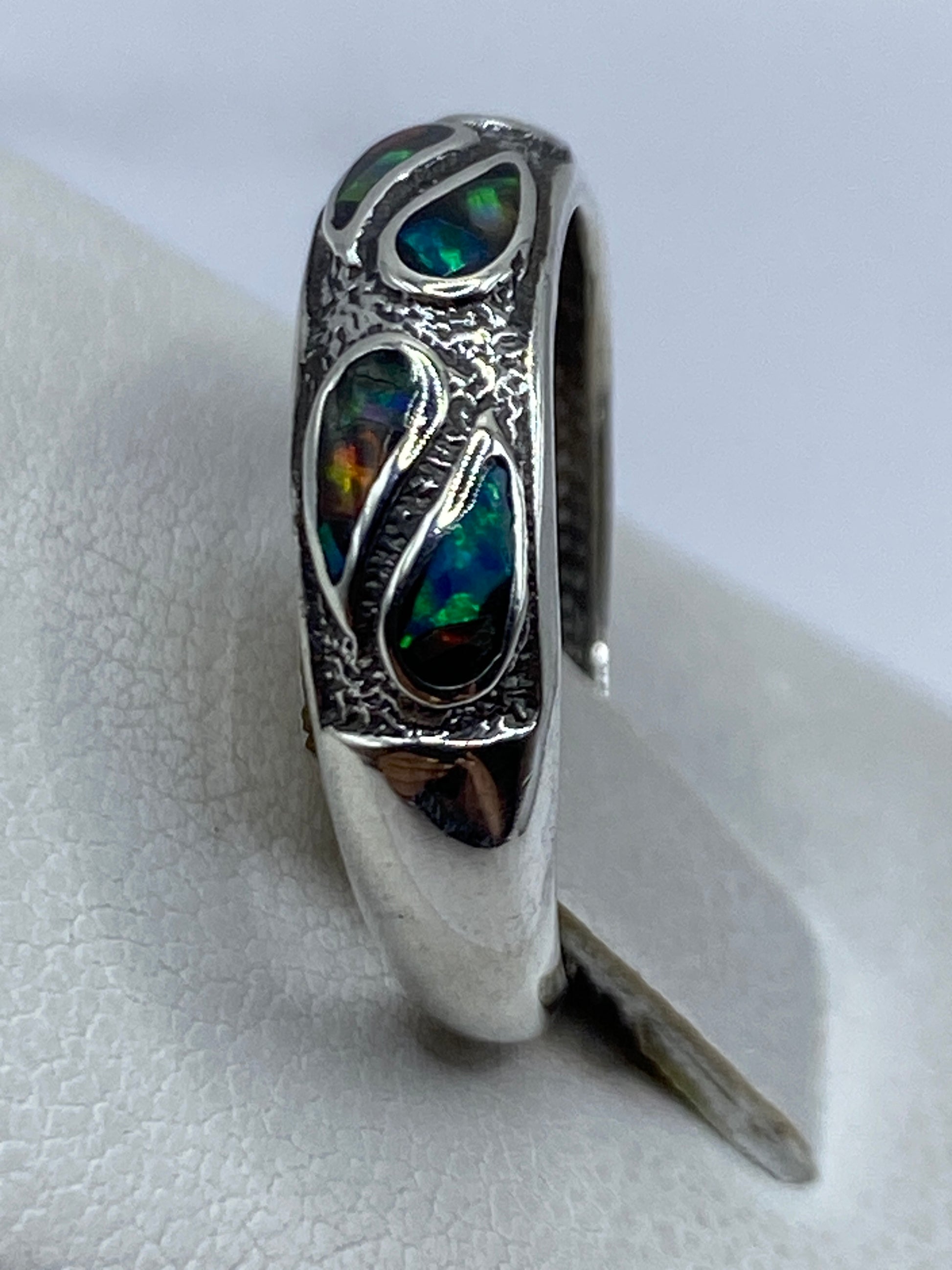 Anillo de ópalo de fuego en dedo, mostrando los tonos dorados y azules cambiantes
