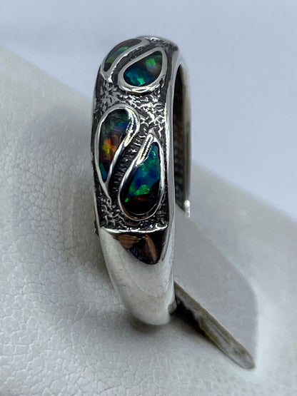 Anillo de ópalo de fuego en dedo, mostrando los tonos dorados y azules cambiantes