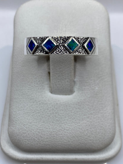 Anillo de plata .950 con ópalo de fuego azul en textura granulada, visto de frente en presentador