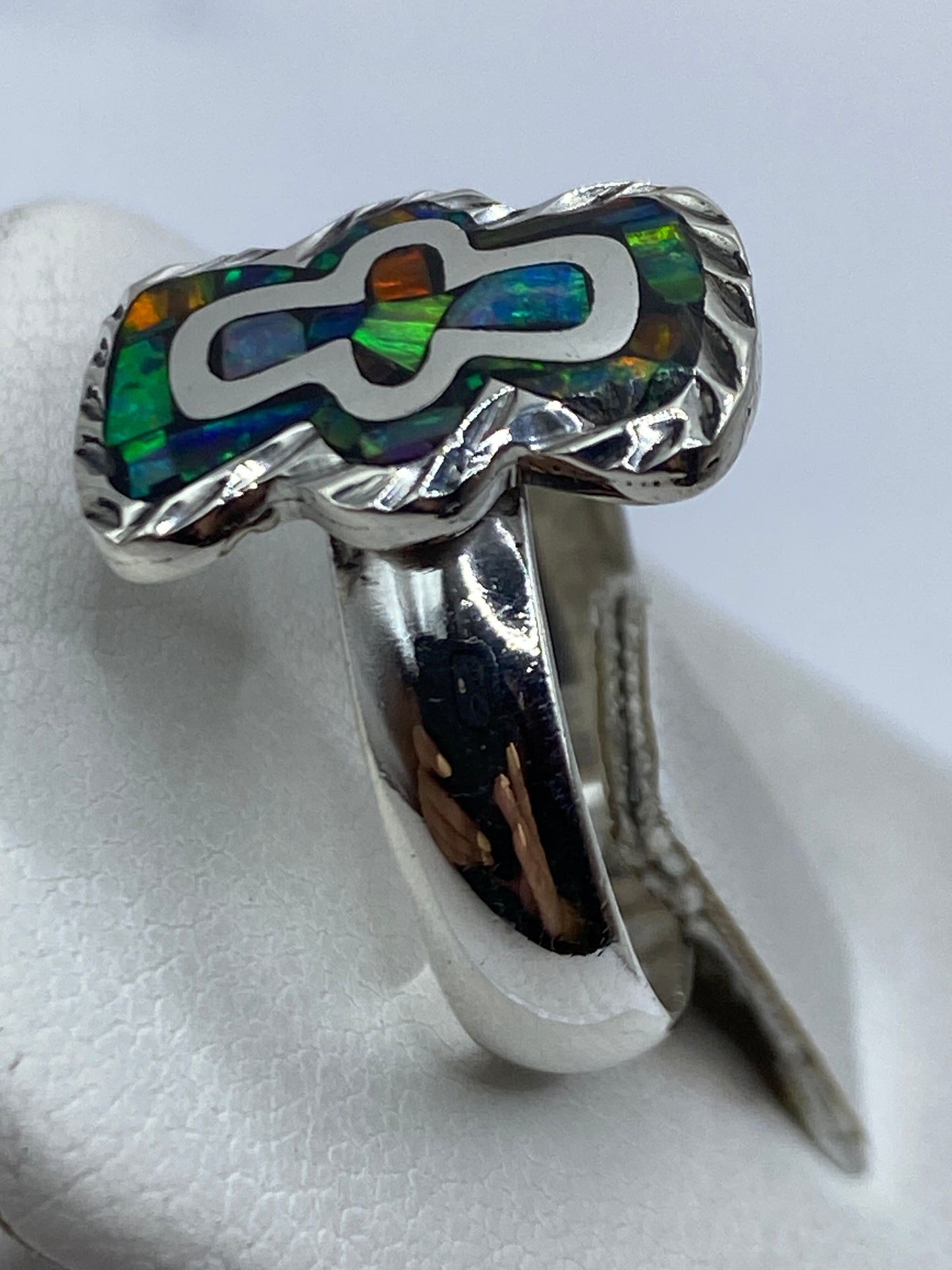 Anillo en la mano mostrando el juego de colores del ópalo de fuego bajo luz natural