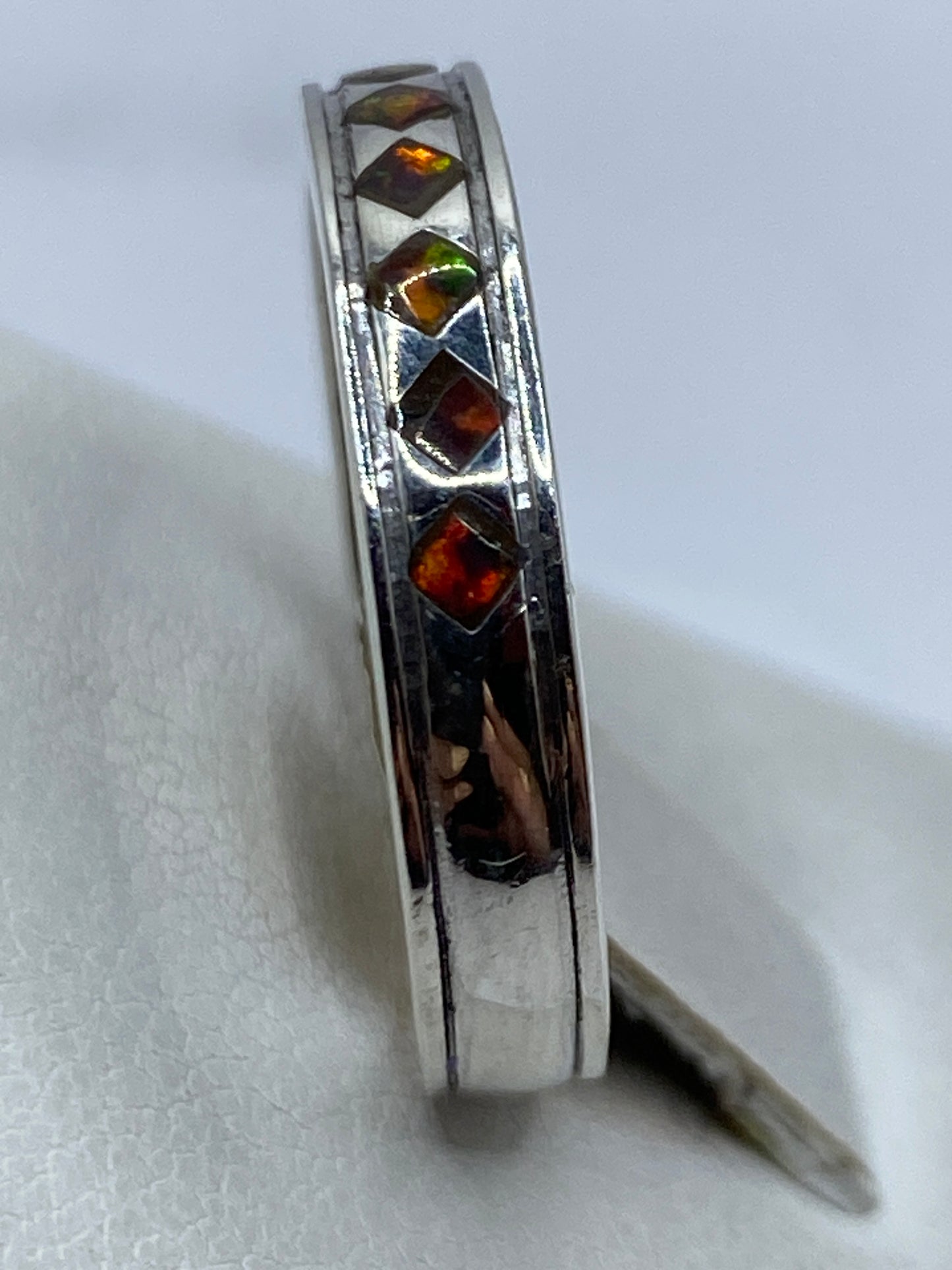 Anillo con ópalo de fuego puesto en dedo, mostrando el juego de luces multicolor