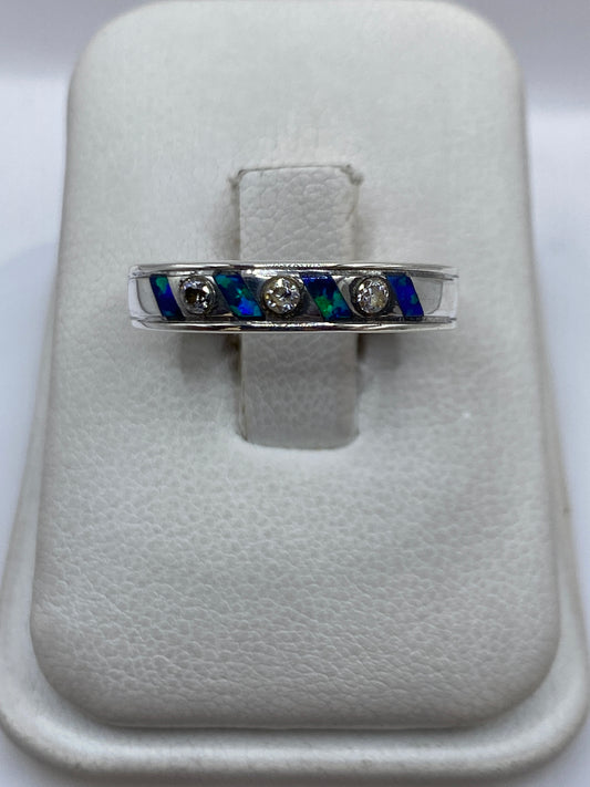 Anillo de plata .950 con ópalo de fuego azul incrustado en banda ancha, sobre blanco