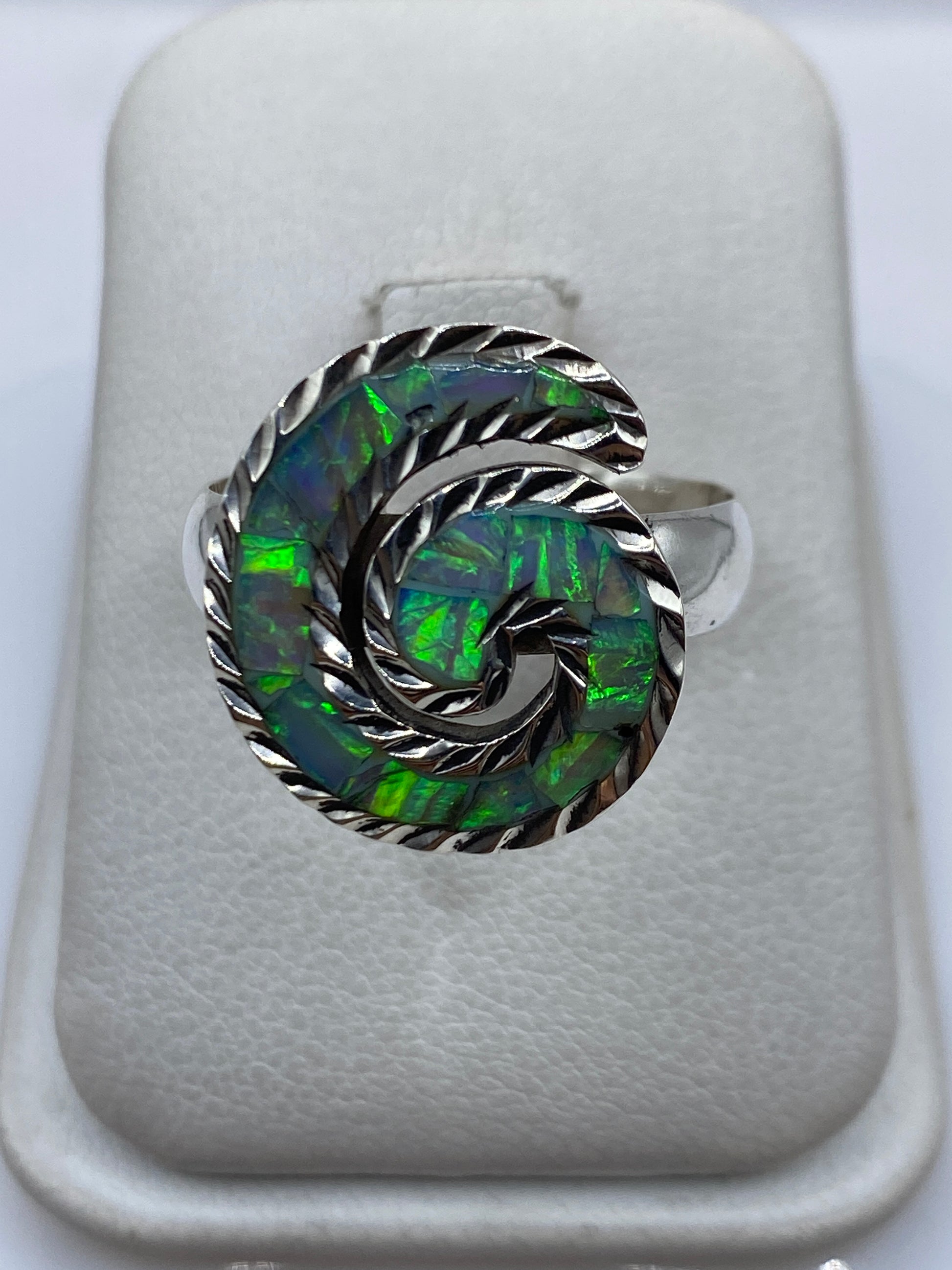 Anillo de plata en espiral con ópalo de fuego azul cielo, mostrando su juego de luz y color