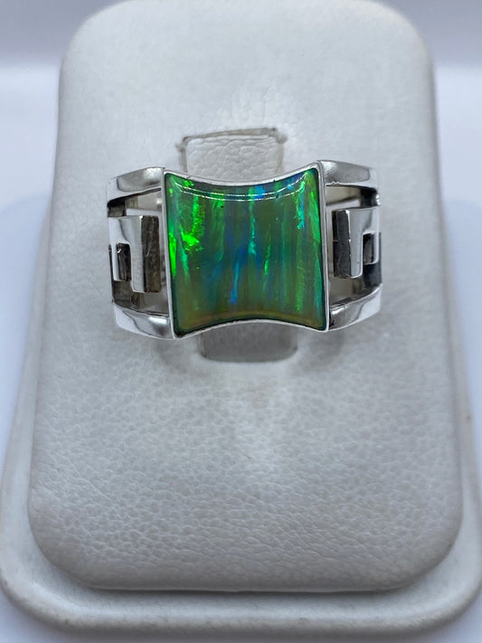 Anillo de plata .950 con ópalo de fuego verde limón en la mano de una mujer, mostrando el brillo arcoíris