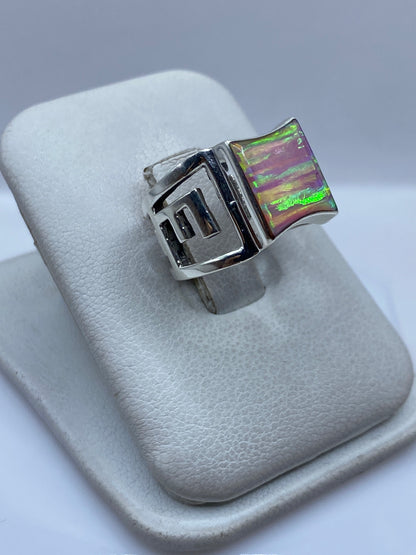 Vista frontal del anillo con ópalo de fuego rosa en estructura geométrica de plata