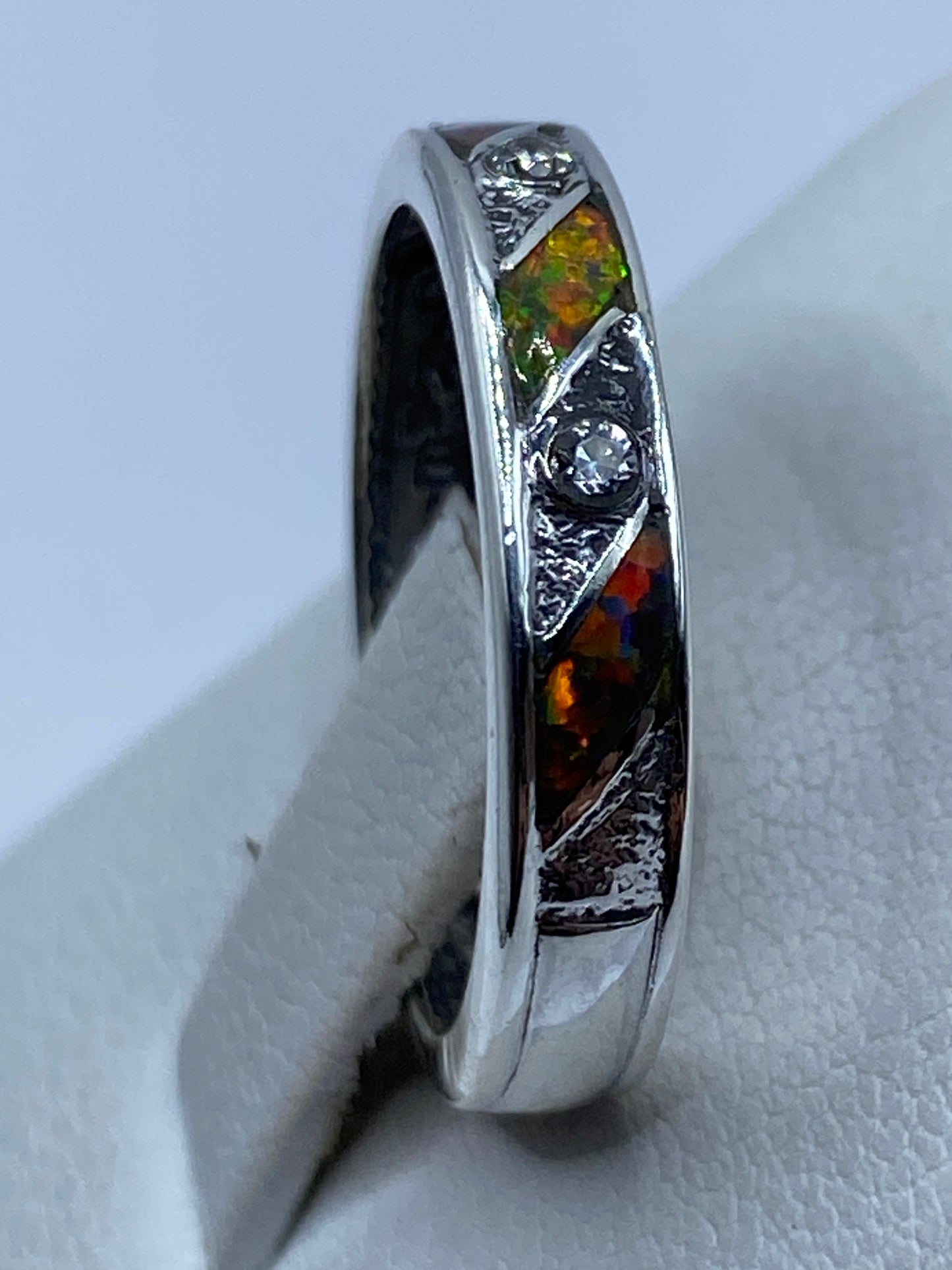 Ópalo multicolor refractando luz en tonos rojo, verde y amarillo en el anillo