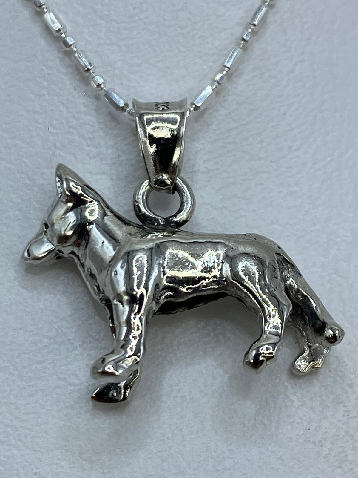 Dije de plata de perro en posición de pie sobre cadena de plata con bolitas