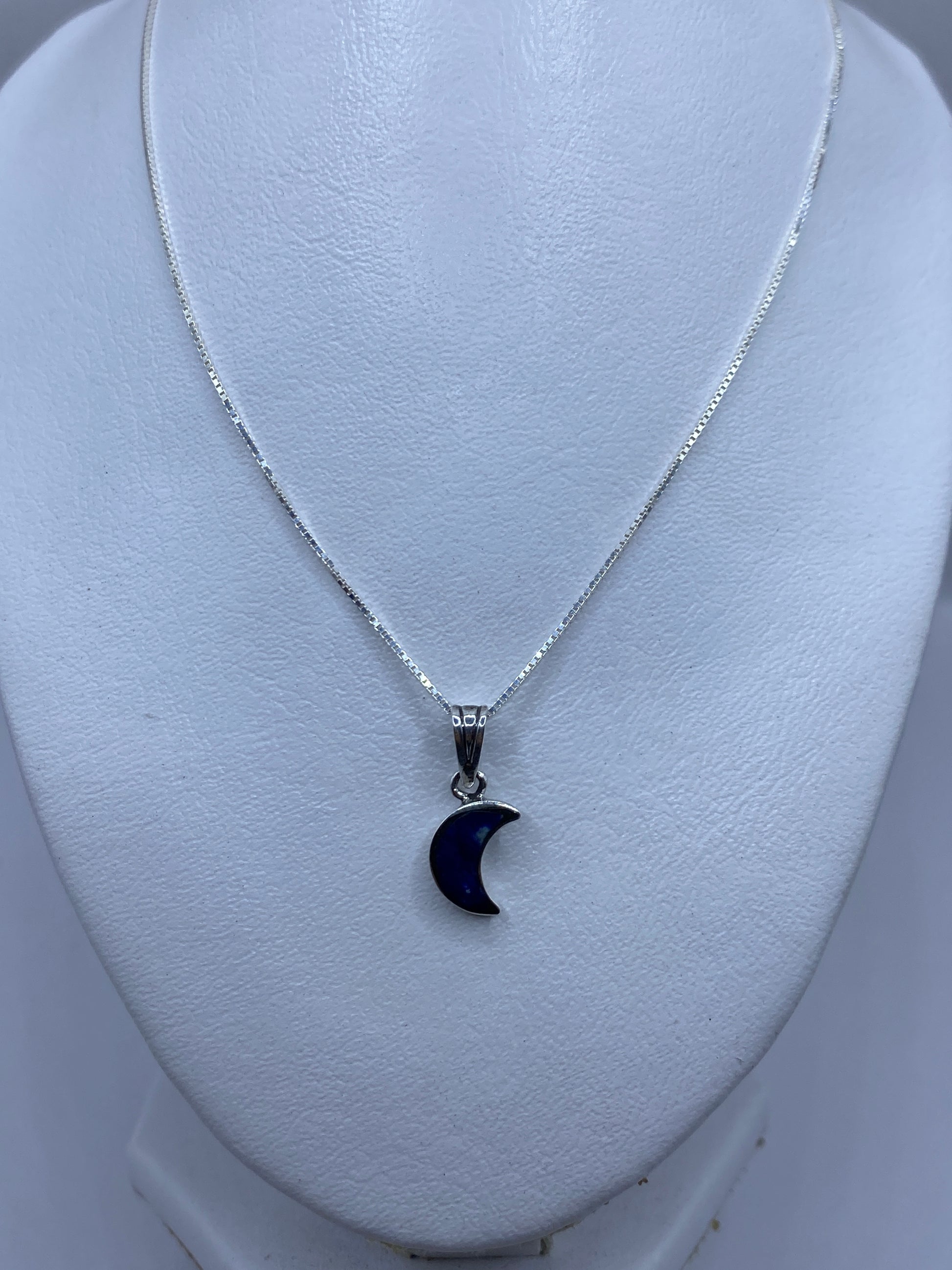 Dije luna colgando de cadena de plata, sobre piel