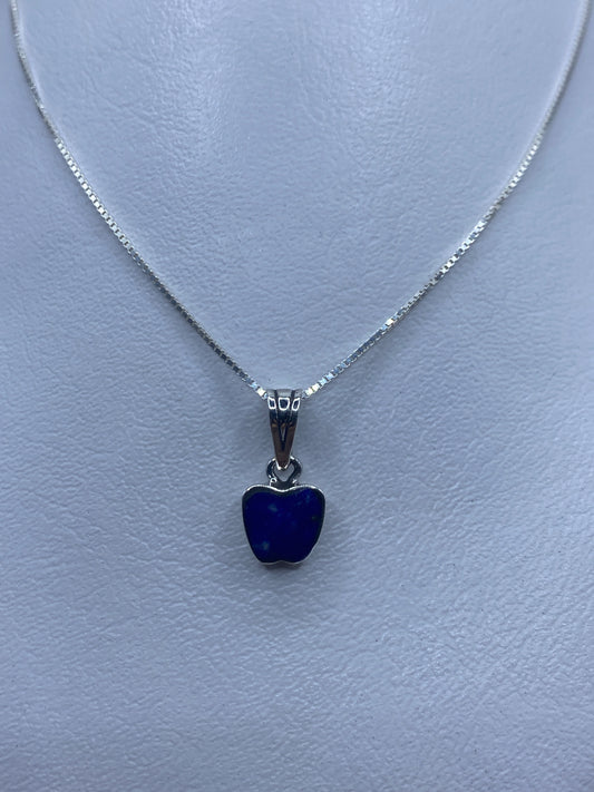 Dije de plata con piedra azul engastada, colgando de cadena delgada