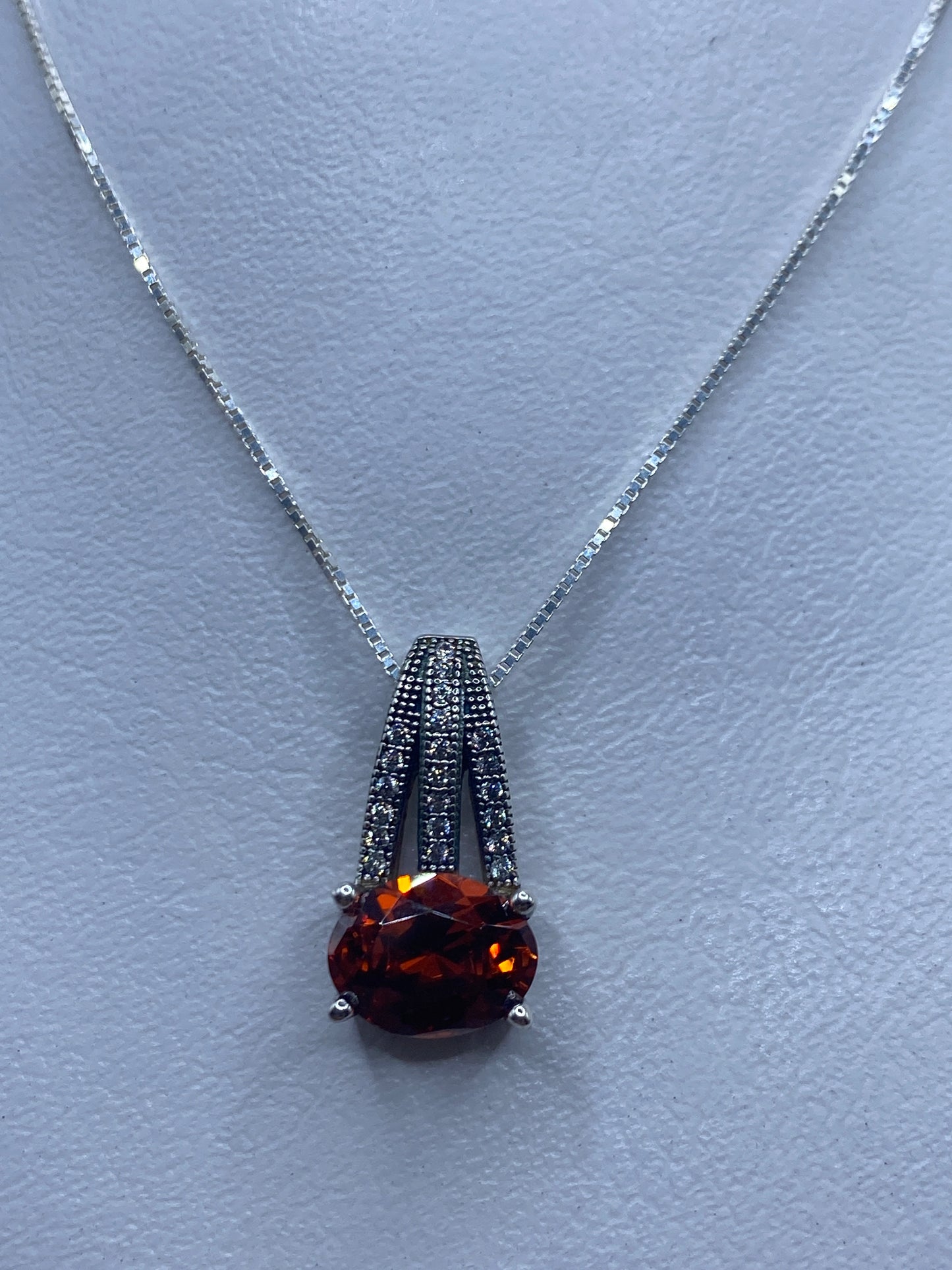 Dije de plata con circonia naranja brillante colgando de cadena delgada