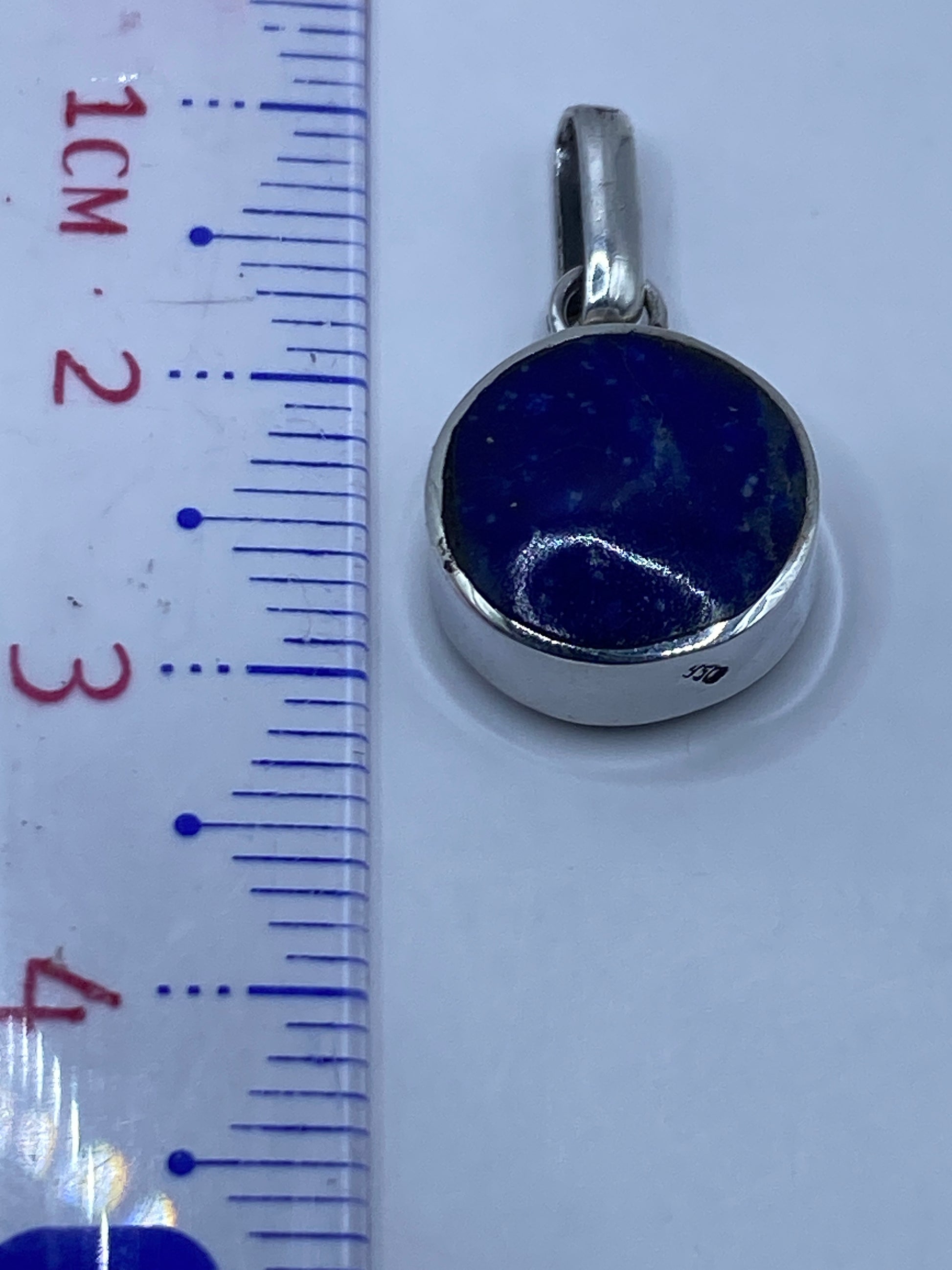 Dije de plata .950 con piedra malaquita sobre fondo blanco con escala de medida
