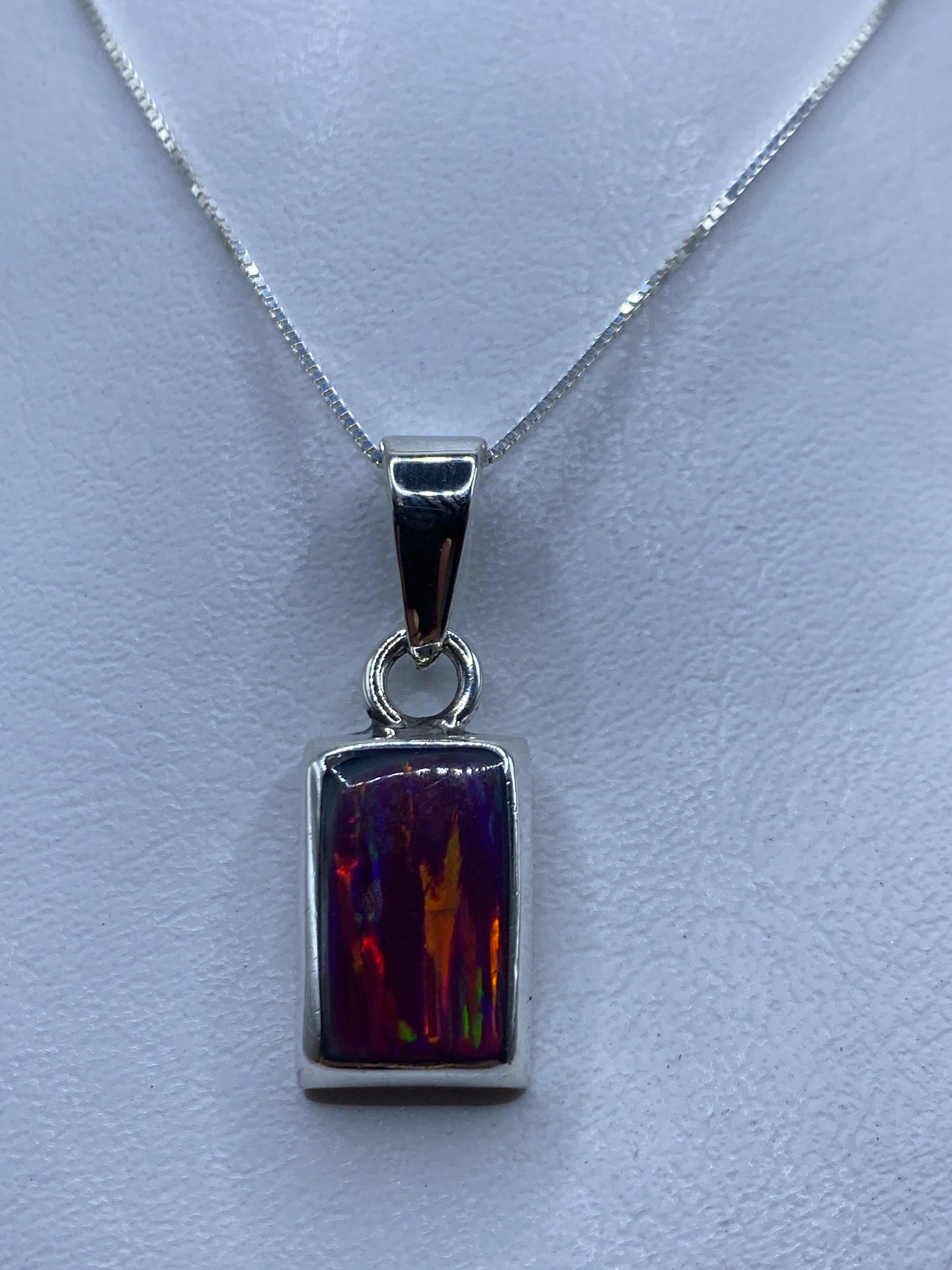 Dije de plata rectangular con ópalo de fuego en tonalidades rosa, naranja y dorado sobre cadena plateada