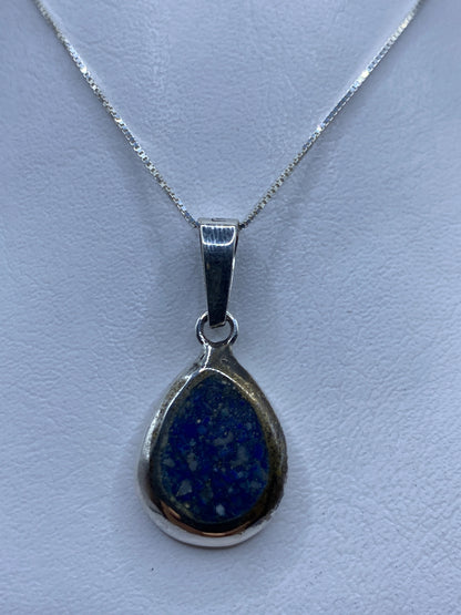 Dije de plata .925 con piedra azul engastada, colgando de una cadena fina