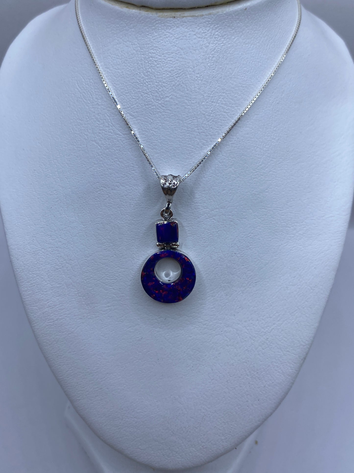 Dije redondo de plata con piedra azul y baño plateado, vista lateral