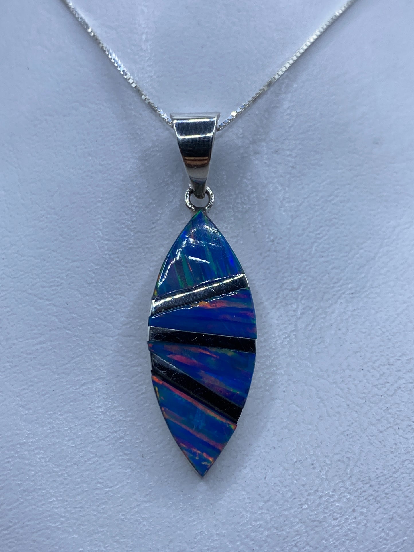 Dije de plata con ópalo de fuego azul incrustado a mano, colgando de cadena en cuello
