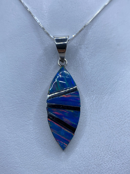 Dije de plata con ópalo de fuego azul incrustado a mano, colgando de cadena en cuello