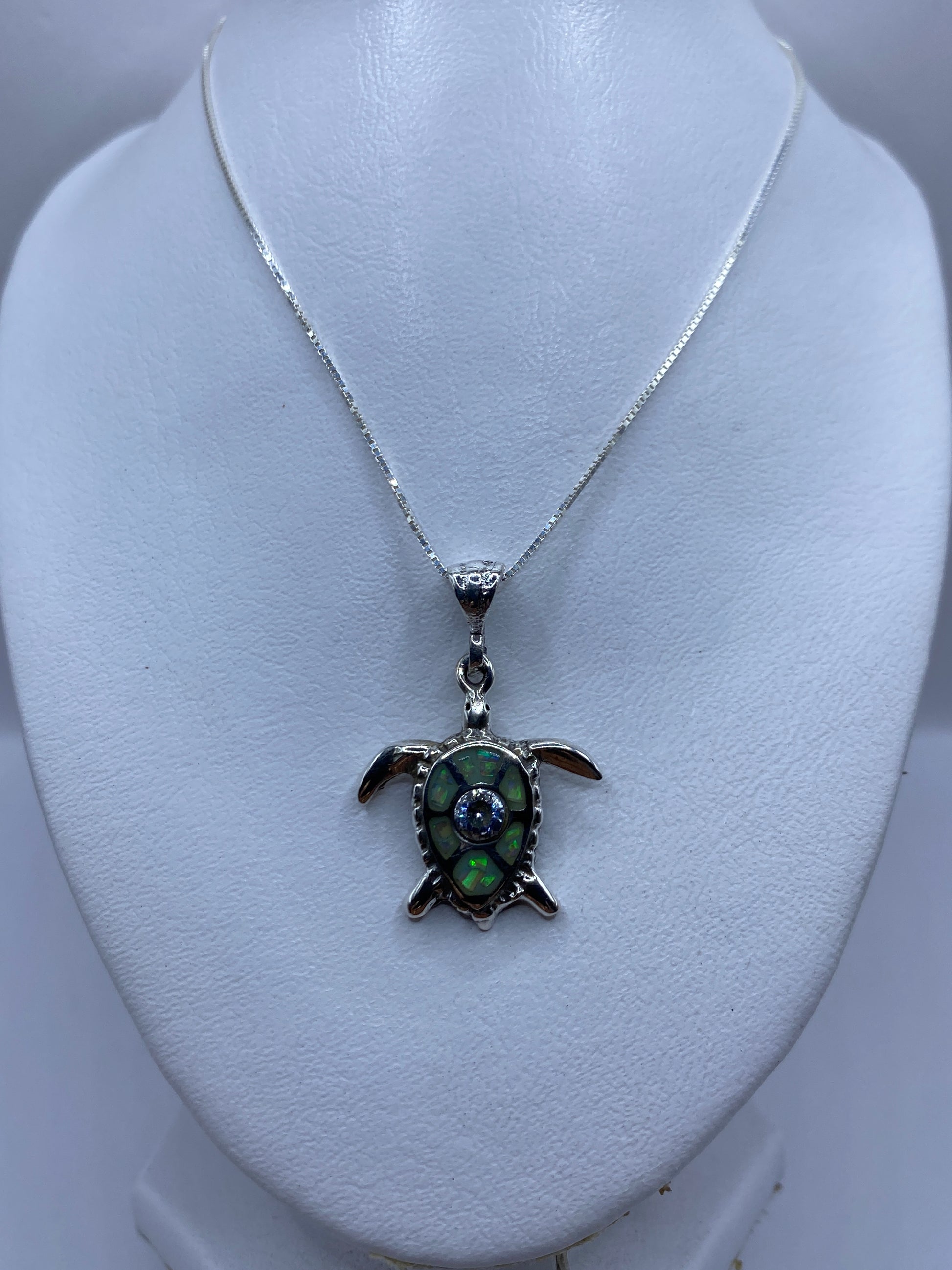Vista frontal del dije de tortuga: ópalo multicolor brillando en el centro