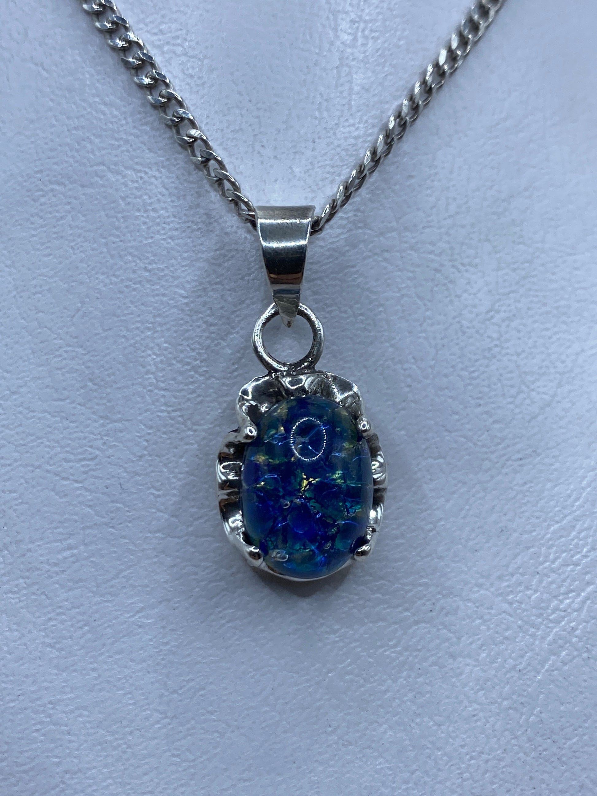 Dije de plata .925 con piedra azul engastada, colgando de una cadena de plata