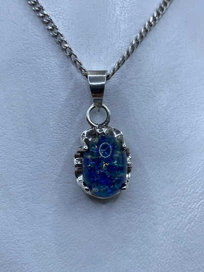 Dije de plata .925 con piedra azul engastada, colgando de una cadena de plata