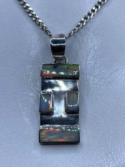 Dije de plata .950 rectangular con ópalo de fuego y dos engastes geométricos sobre fondo claro