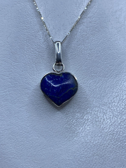 Dije de plata en forma de corazón con malaquita verde, colgado en cadena de plata sobre fondo gris claro