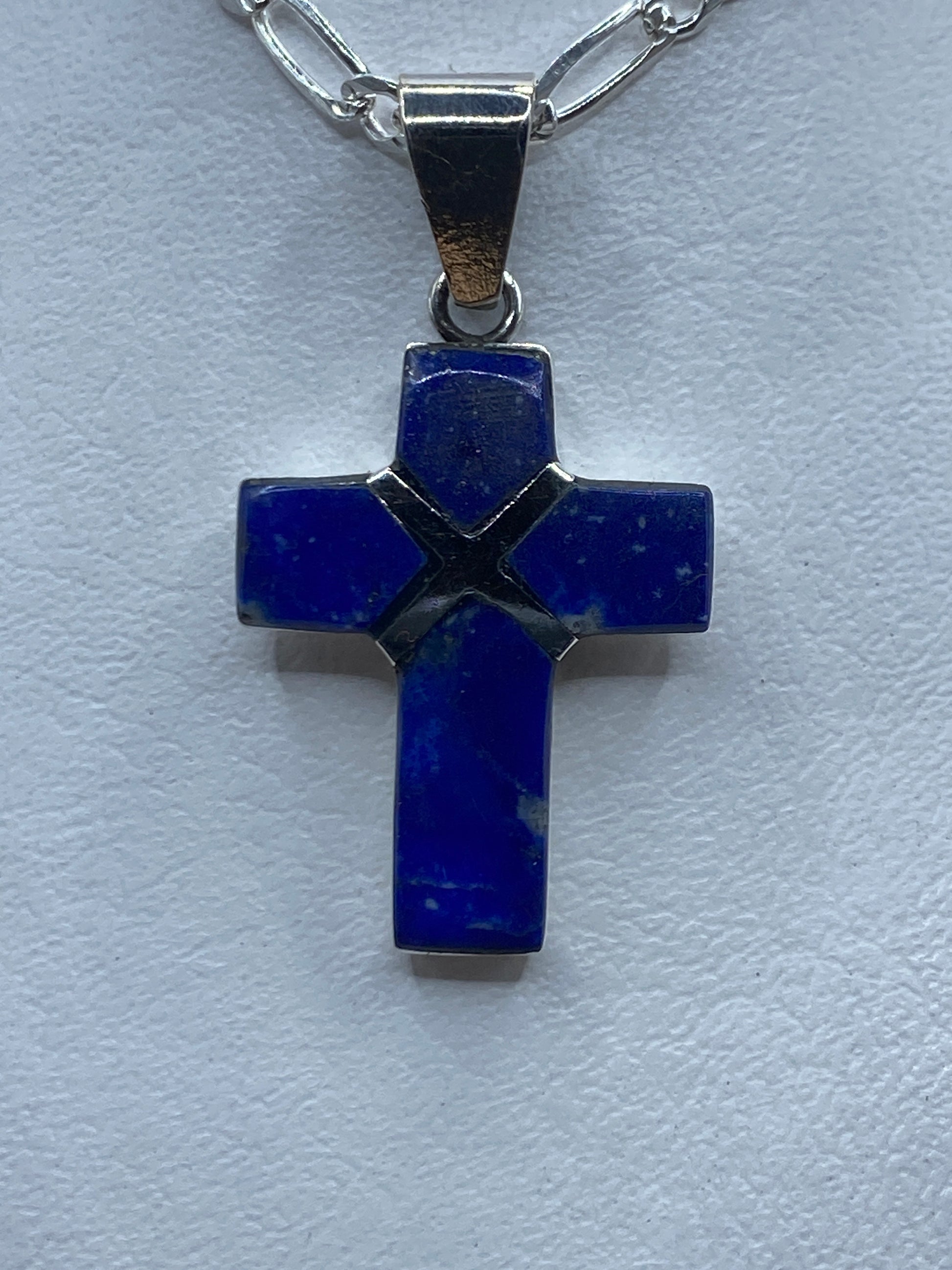 Dije cruz de plata .950 con lapislázuli azul profundo engastado, colgando de cadena plateada