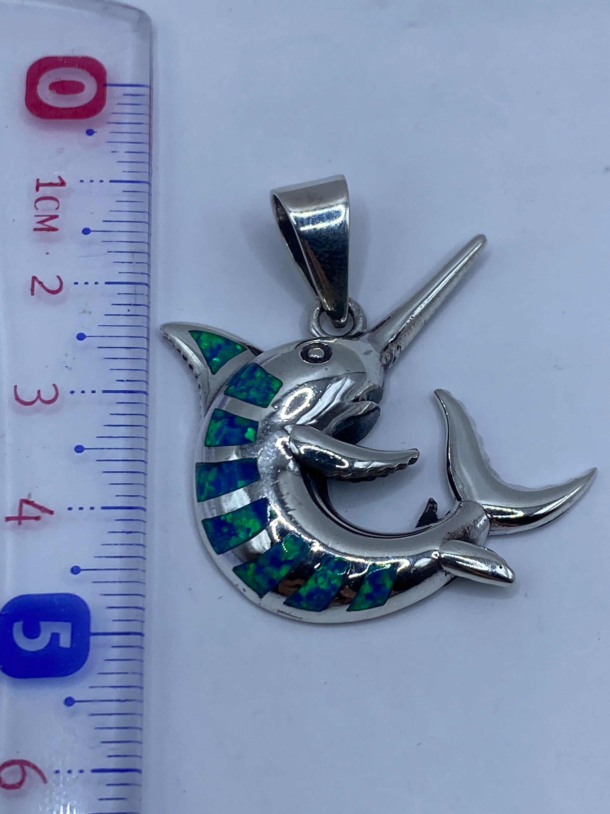 Marlin de plata .950 sobre fondo blanco con medida de escala en centímetros