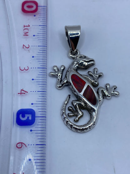Dije lagartija colgando de una cadena de plata, mostrando el tamaño real de 5.7 cm