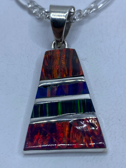 Dije de plata con ópalo de fuego multicolor engastado, sobre fondo blanco