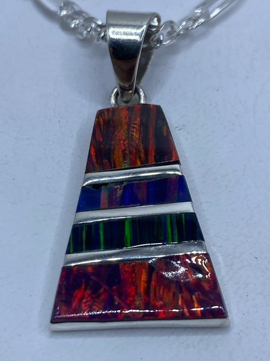 Dije de plata con ópalo de fuego multicolor engastado, sobre fondo blanco