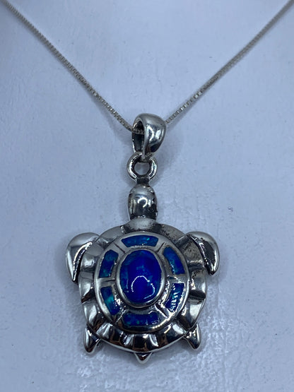 Dije tortuga de plata .950 con ópalo de fuego azul colgado en cadena plateada