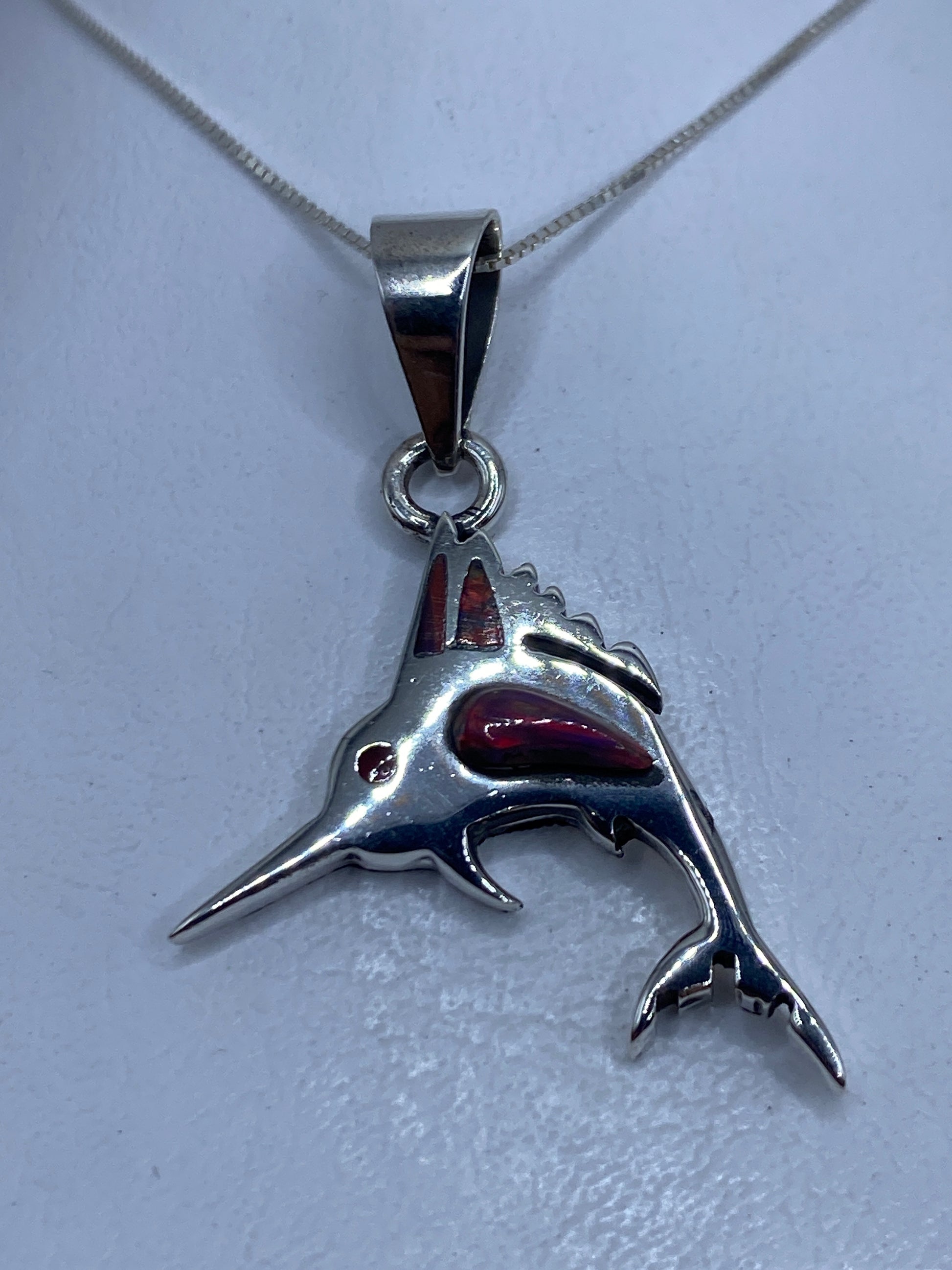 Dije de tiburón en plata .950 con ópalo de fuego multicolor, visto de frente sobre fondo blanco