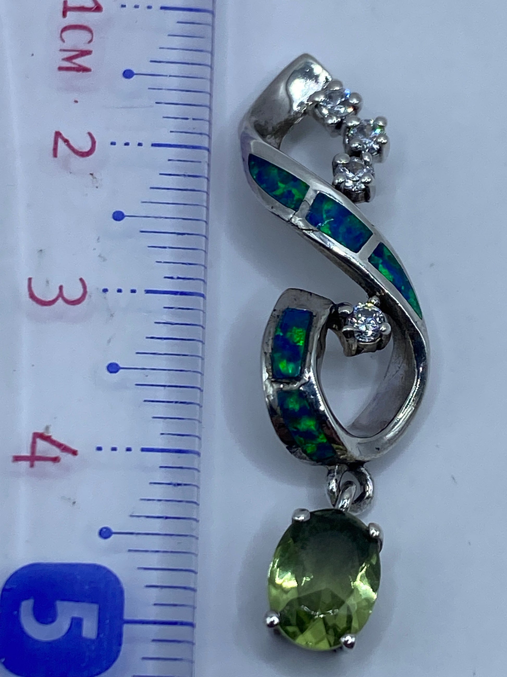 Dije de 5.5 cm de largo junto a una regla, mostrando su tamaño real en la mano