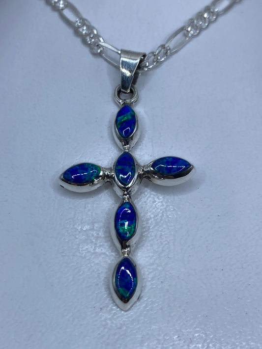 Dije cruz de plata con ópalo de fuego azul engastado, colgando de cadena