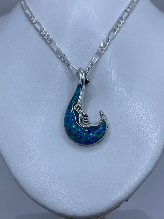 Detalle frontal del dije luna mostrando la incrustación del ópalo de fuego y los reflejos azules