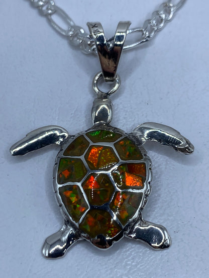 Dije tortuga de plata .950 con ópalo de fuego amarillo incrustado, colgando de una cadena Figaro pulida