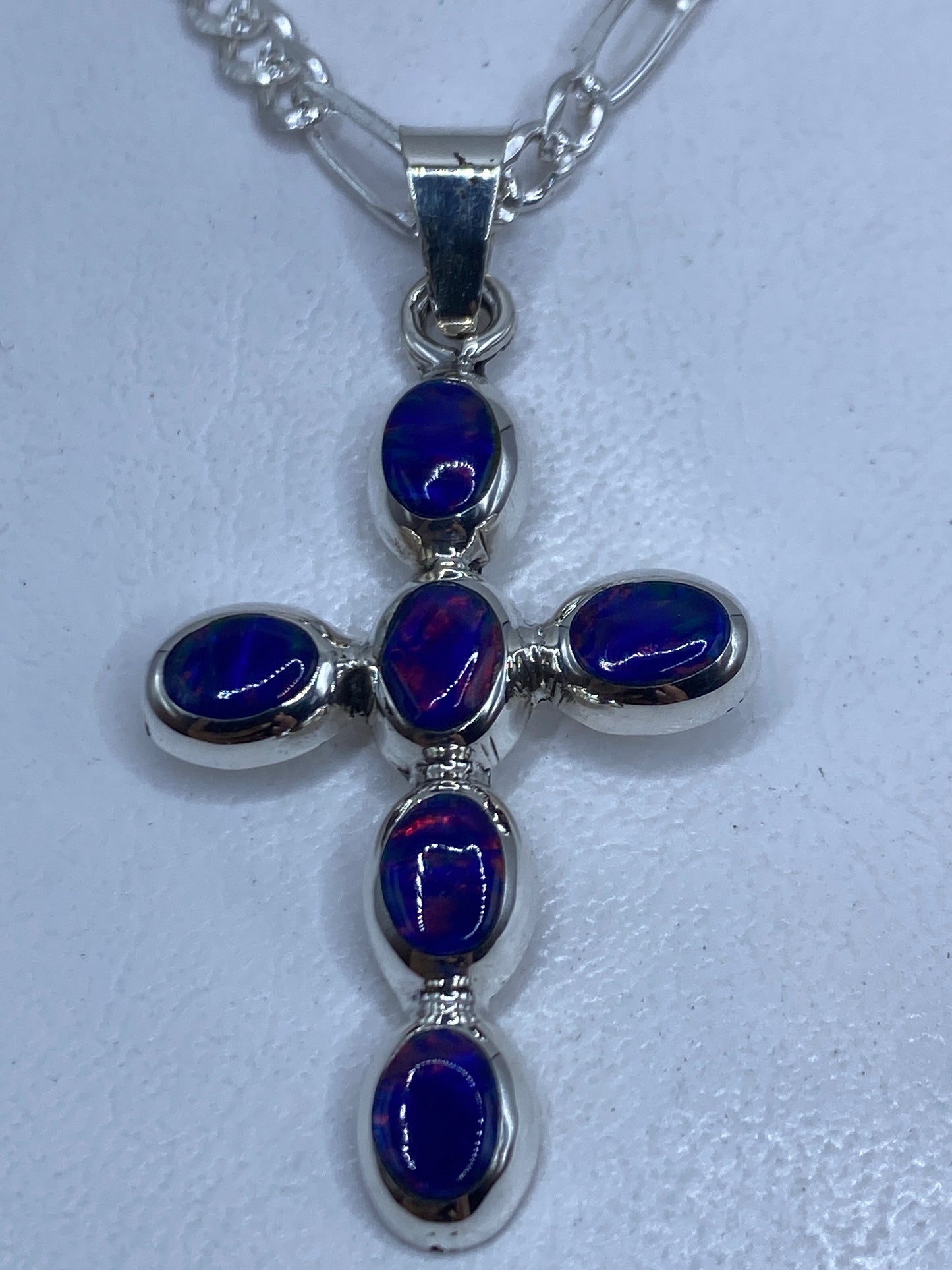 Cruz dije de plata .950 con ópalo de fuego azul, vista frontal sobre cadena