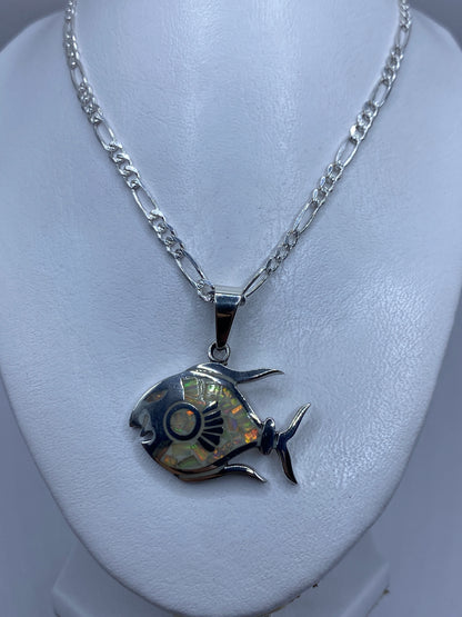 Dije de plata artesanal de Taxco en forma de pez, colgando de una cadena figaro