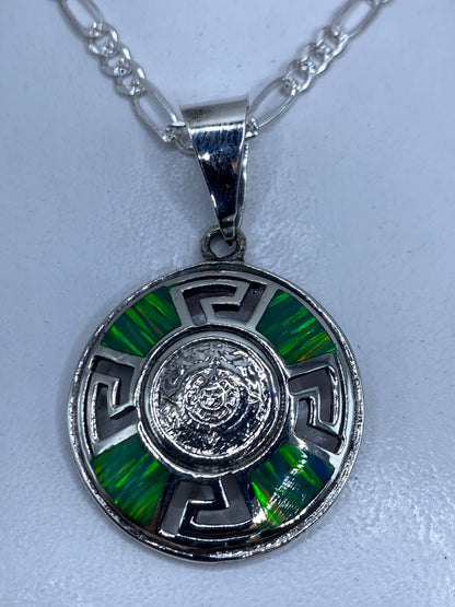 Dije circular de plata con ópalo de fuego verde incrustado, diseño prehispánico con grecas geométricas