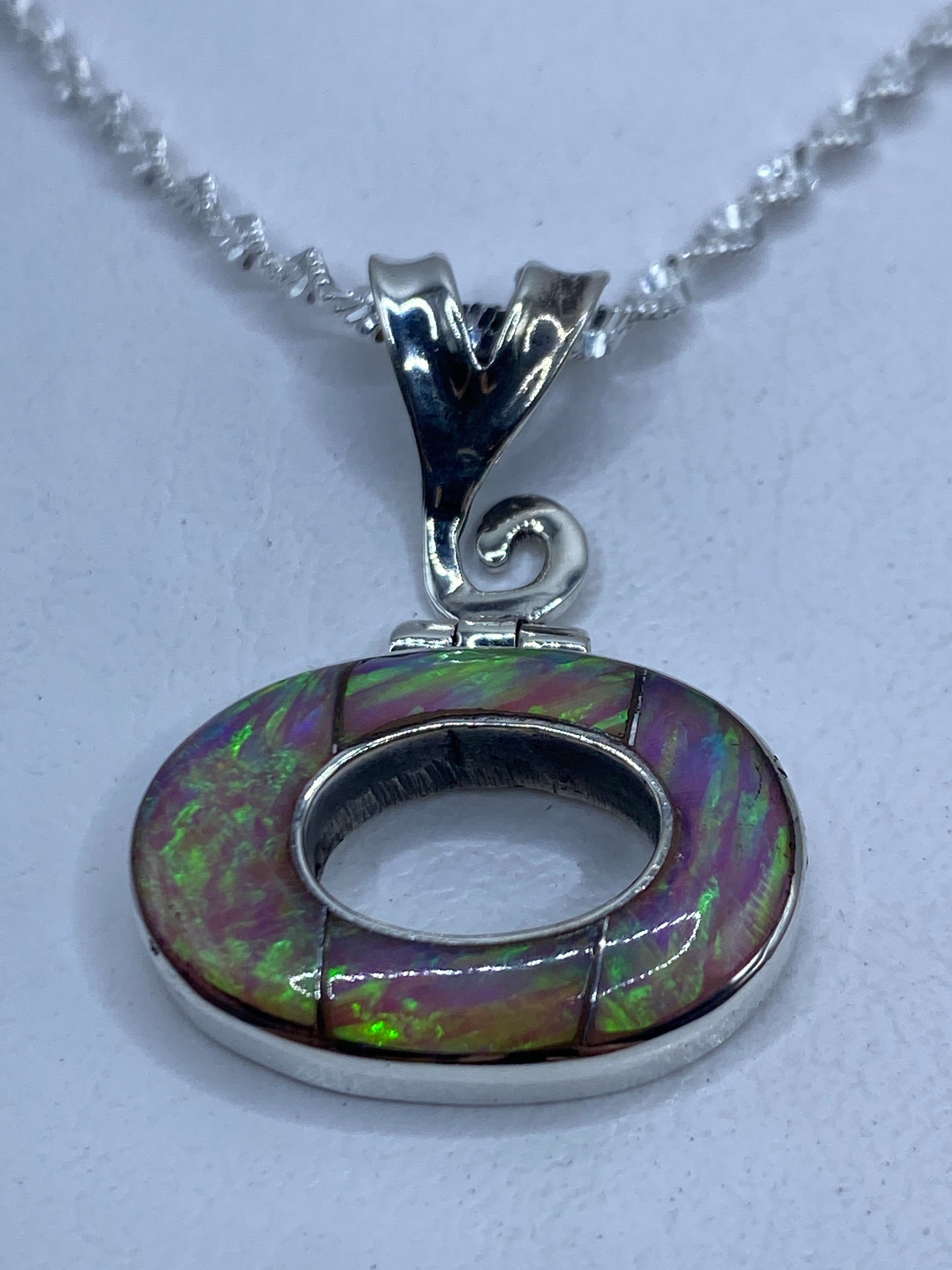 Dije ovalado de plata .950 con Ópalo de Fuego rosa incrustado en forma de gota, colgando de una cadena plateada