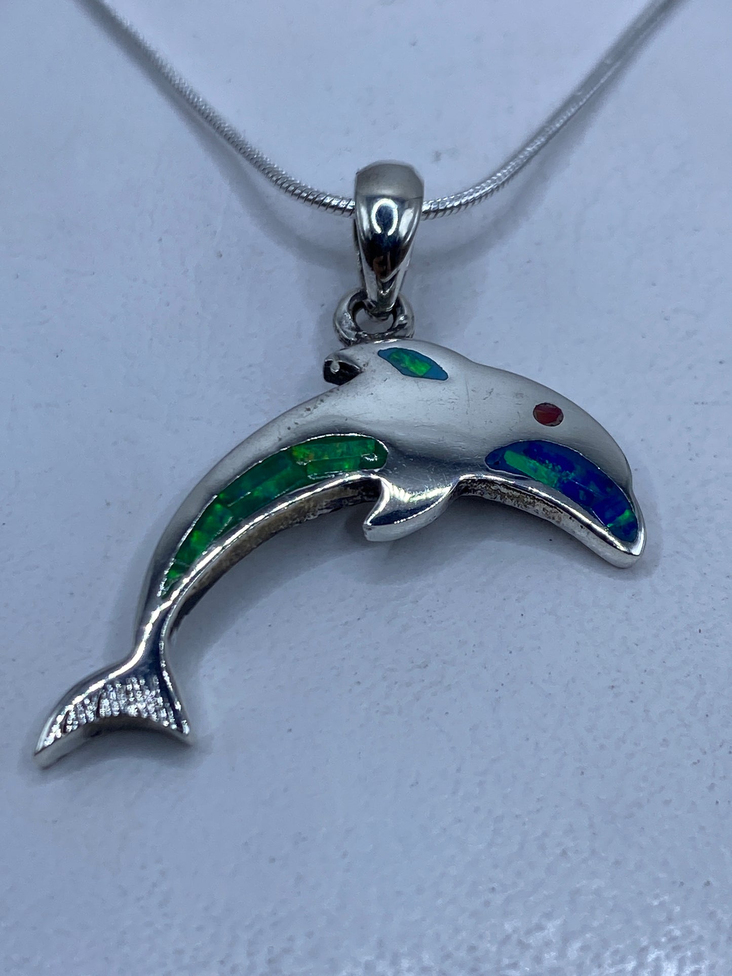 Dije de plata con ópalo de fuego multicolor en tonos verdes y azules, colgado en cadena de plata